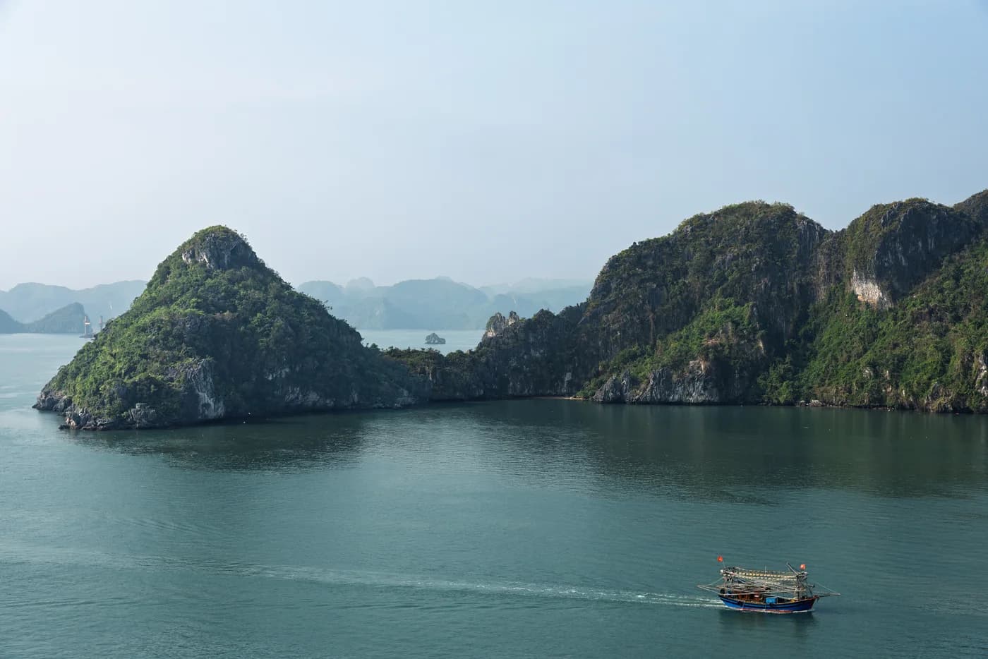 Limestone islands and a small boat in Ha Long Bay, photographed in 2024