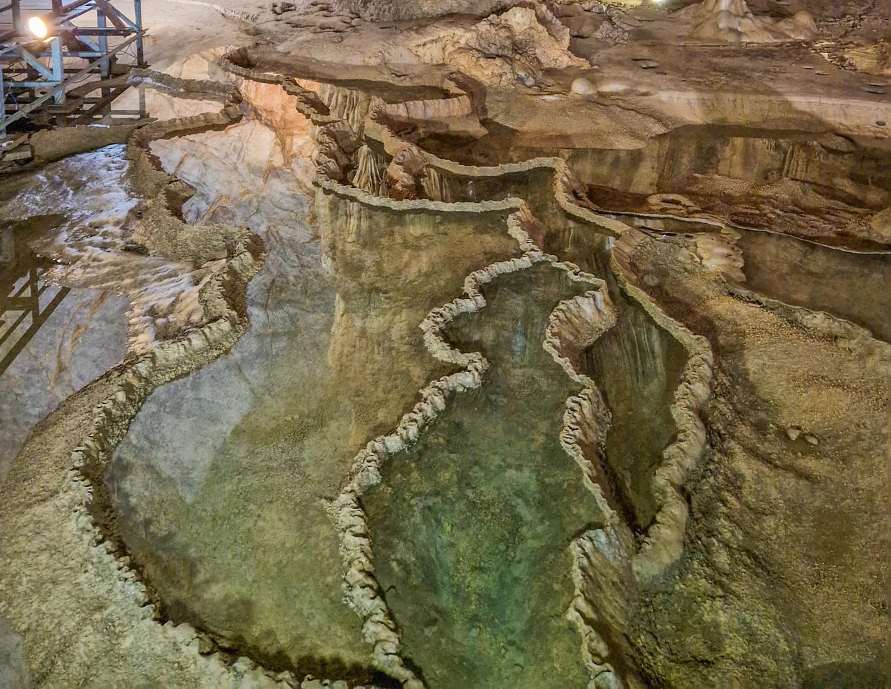 パラダイス洞窟の床の水がたまった段状の縁と、脇の木製見学通路、2024年11月