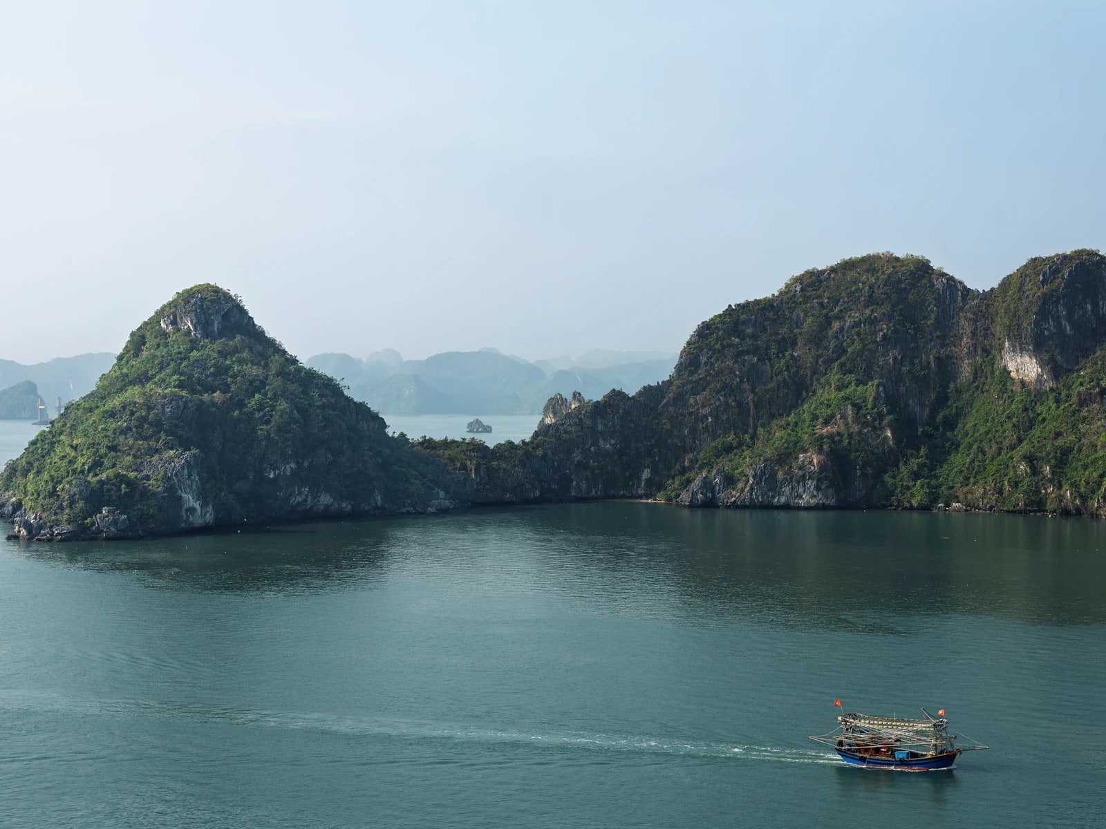 Limestone islands and a small boat in Ha Long Bay